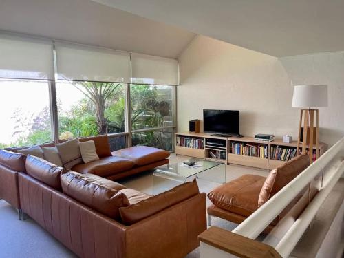 a living room with a couch and a television at Riversdale Retreat - w. beach & golf course access in Mollymook