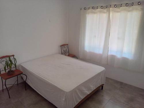 Un dormitorio con una cama blanca y una ventana. en Hospedagen Casa Verde, en Búzios