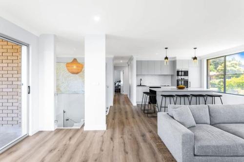 a living room with a couch and a kitchen at Mollymook Delight - with easy ocean & golf access in Mollymook
