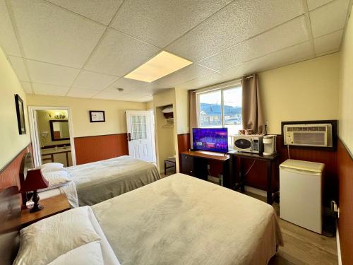 a hotel room with two beds and a computer on a desk at Merritt Lodge in Merritt