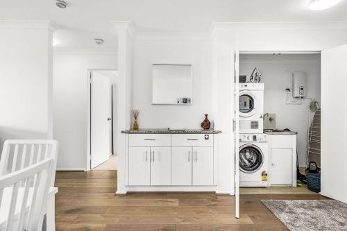a white laundry room with a washer and dryer at 6 Light Bright Home in South Perth in Perth