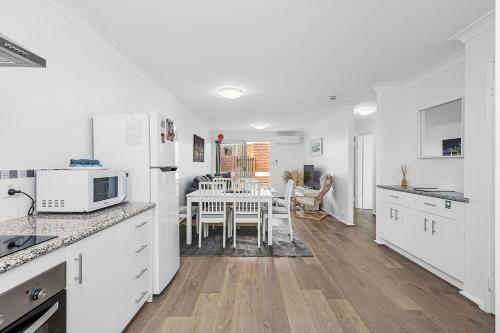 a kitchen with white appliances and a table with chairs at 6 Light Bright Home in South Perth in Perth