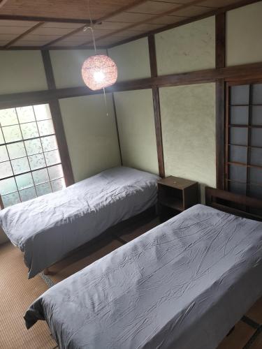 two beds in a room with two windows at 貸切ゲストハウス スポパー徒歩10分 Guesthouse near sports park in Naruto