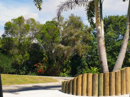 a wooden fence in a park with a palm tree at 1770 Beachside Backpacker in Agnes Water