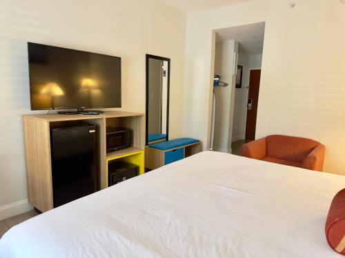 a hotel room with a bed and a flat screen tv at Days Inn & Suites by Wyndham Lakeland in Lakeland