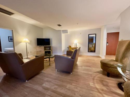 a living room with chairs and a couch and a tv at Days Inn & Suites by Wyndham Lakeland in Lakeland