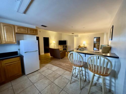 a kitchen with a white refrigerator and two bar stools at Days Inn & Suites by Wyndham Lakeland in Lakeland