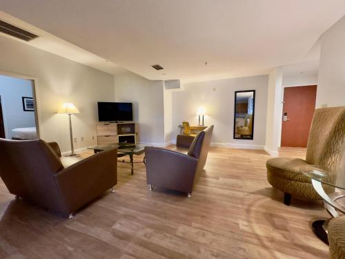 a living room with couches and chairs and a television at Days Inn & Suites by Wyndham Lakeland in Lakeland