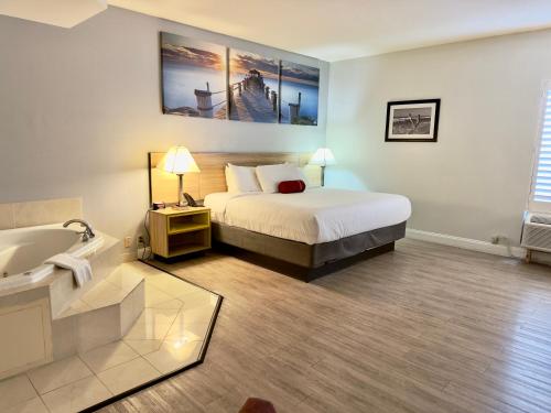 a bedroom with a bed and a tub and a sink at Days Inn & Suites by Wyndham Lakeland in Lakeland