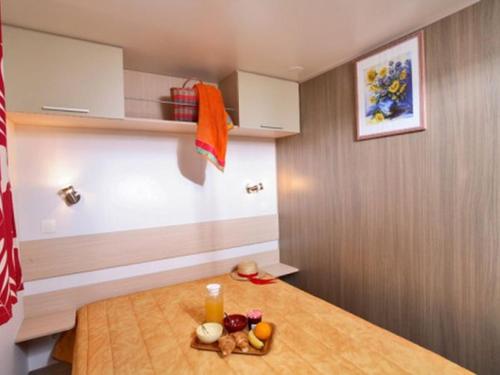 a kitchen with a wooden table with food on it at Mobil home 6 pers avec terrasse - API-1-52-172 in Meyrueis