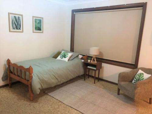 1 dormitorio con cama, silla y ventana grande en Lake Edge at Lake Conjola, en Conjola
