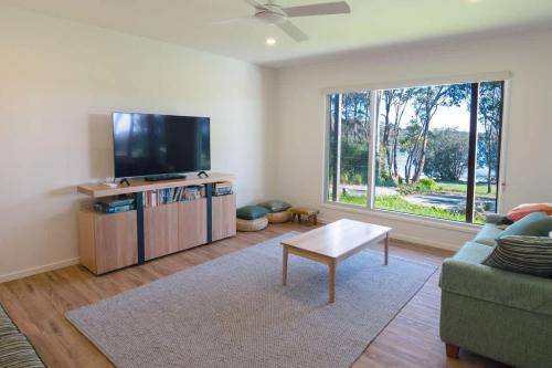 a living room with a flat screen tv and a couch at Mherringa at Bawley - enjoy panoramic ocean views in Bawley Point