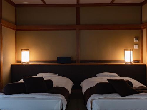 two beds in a room with two lights on the wall at Ichiboukan Hanare Kai in Kyotango