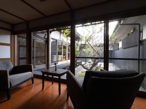 a living room with chairs and a table and windows at Ichiboukan Hanare Kai in Kyotango