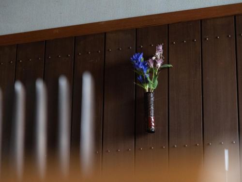 a vase with purple flowers in it on a wall at Ichiboukan Hanare Kai in Kyotango