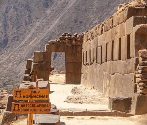 a building with a sign in front of a mountain at Hotel Valle Mistico in Ollantaytambo