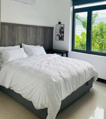 a bedroom with a large white bed with a window at Suoi Da Villa in Ðồn Bãi Cả