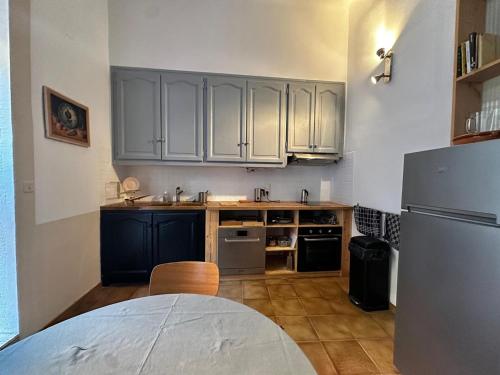 a kitchen with white cabinets and a table and a refrigerator at Port-Vendres: Appartement T2 avec terrasse proche port - FR-1-309-537 in Port-Vendres