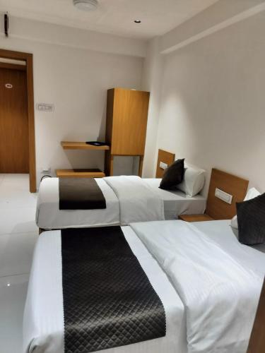 two beds in a hotel room with white and black at Hotel Pine View in Rajkot