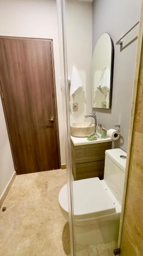 a bathroom with a toilet and a sink and a mirror at Jungle Guardian - Rooftop Pool & Beach Club in Zona Hotelera Tulum in Tulum