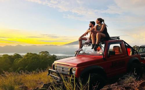 two people sitting on the top of a red truck at Unagi Wooden Villas by Emana in Ubud