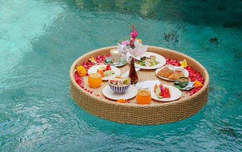 a miniature table with food and drinks in the water at Unagi Wooden Villas by Emana in Ubud