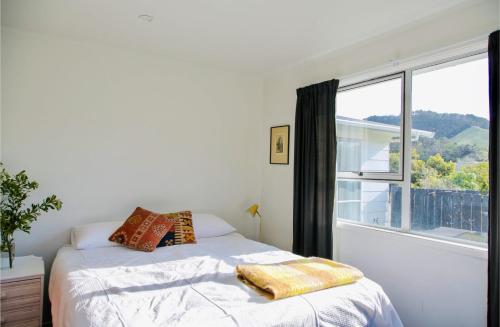a bedroom with a bed and a large window at Coastal Retreat - Whiritoa Holiday House in Whiritoa