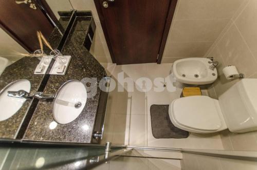 a bathroom with a white toilet and a sink at Comfy Villa Morra Apt in Asuncion