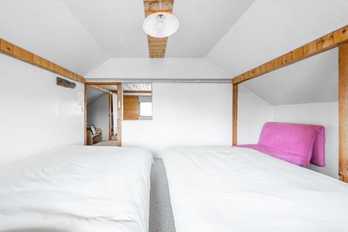 1 dormitorio con 2 camas y silla rosa en Peace Garden Furano, en Nakafurano