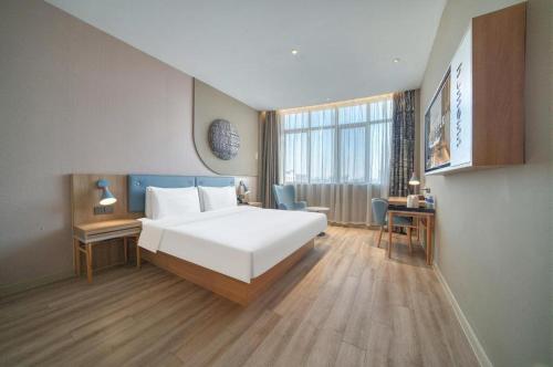 a bedroom with a large white bed and a desk at Home Inn Neo Zhuji Zhejiang Agriculture and Forestry University in Shaoxing