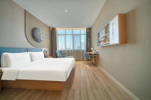a hotel room with a large white bed and a desk at Home Inn Neo Zhuji Zhejiang Agriculture and Forestry University in Shaoxing