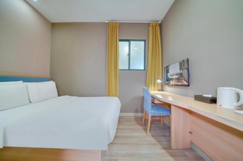 a hotel room with a bed and a desk with a computer at Home Inn Neo Zhuji Zhejiang Agriculture and Forestry University in Shaoxing