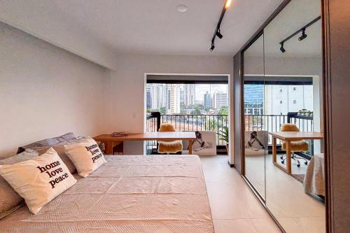 a bedroom with a bed and a table and a balcony at BSide Faria Lima Pinheiros in Sao Paulo