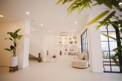 a white living room with a white couch and a plant at GOtoBED in Mutiara Airport
