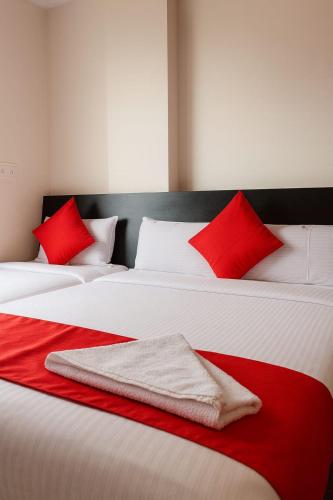 two white beds with red pillows in a room at Dreamzz Comforts in Chikmagalūr
