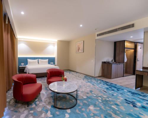 a hotel room with a bed and two red chairs at The Skye Phnom Penh Hotel & Apartments in Phnom Penh