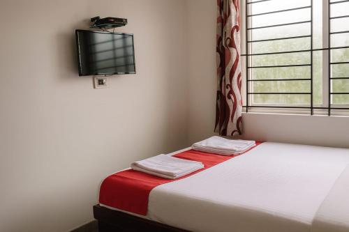 a room with a bed and a tv on the wall at Dreamzz Comforts in Chikmagalūr