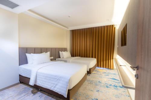 a hotel room with two beds and a television at The Skye Phnom Penh Hotel & Apartments in Phnom Penh