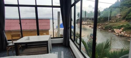 a room with a view of a river through windows at Waterfall Guesthouse1 in Phumĭ Kaôh Rŏng