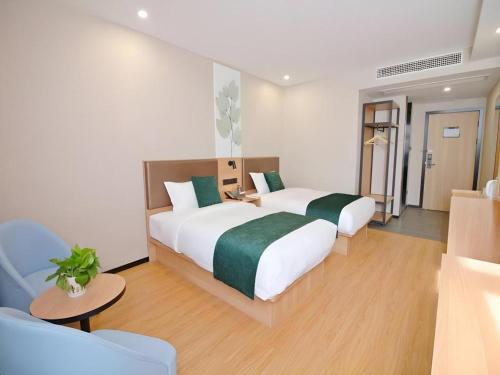 a hotel room with two beds and a couch at GreenTree Inn Express Zhangjiagang Hexing Town Shazhou Professional Institue of Technology in Qiwei