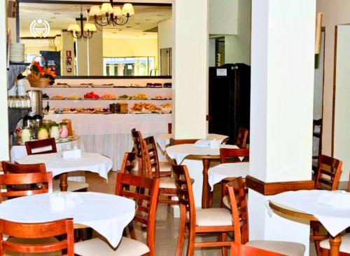 a restaurant with white tables and wooden chairs at Hotel Marbella in Punta del Este