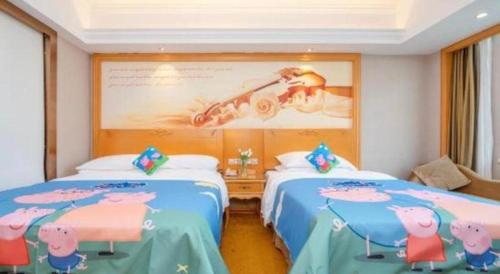 two beds in a room with a large picture on the wall at Vienna Hotel Guangxi Fangcheng in Fangcheng