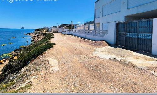 a dirt road next to a building next to the water at Villa Sounine Rafraf in Bizerte