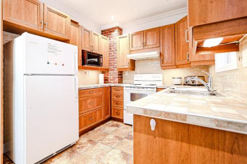 a kitchen with wooden cabinets and a white refrigerator at Royal Level-5 bedrooms avec 2 places de parking in Montréal