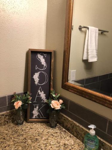 a bathroom sink with a picture and flowers on a counter at Full Kitchen, Beautiful & Brilliant Apt B in College Station
