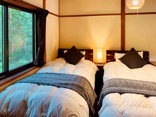 two beds in a room with two windows at Moyai House in Hakuba
