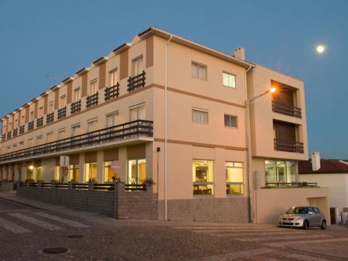 a building with a car parked in front of it at Hotel Miramar - São Pedro de Moel in São Pedro de Moel
