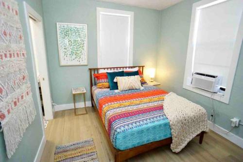 a bedroom with a bed with a colorful blanket and a window at BOHO Vibes! Walk 2 Beach & Ocean Center! in Daytona Beach