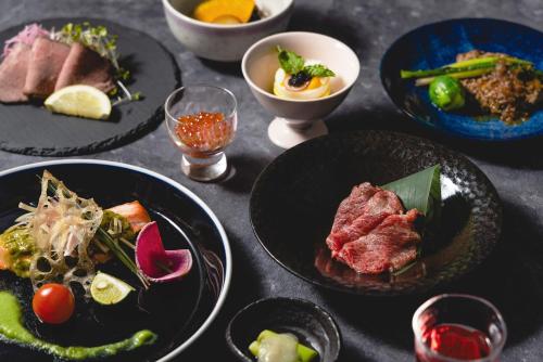 a table with plates of food and bowls of food at Shikishimaso in Higashikawa