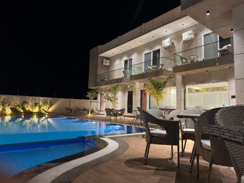 a building with a swimming pool with tables and chairs at Infinity Resort & Restaurant in Gauli Palāsia
